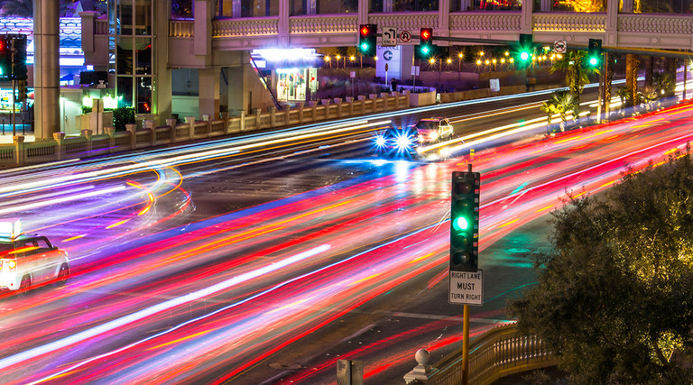 Photo taken above Las Vegas Boulevard (the strip), at night. Many car's light at blurred motion